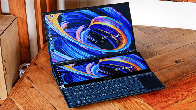 A foldable black laptop with two screens above a small keyboard sat on a brown wooden desk.