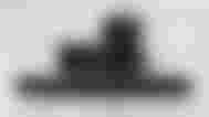 A long black rectangular soundbar with two speakers, a remote, and a subwoofer behind it.