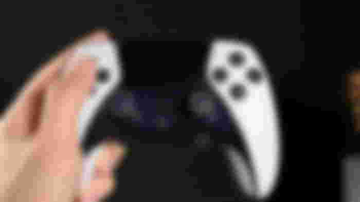 Dualsense Edge Held in the left hand on a black background.