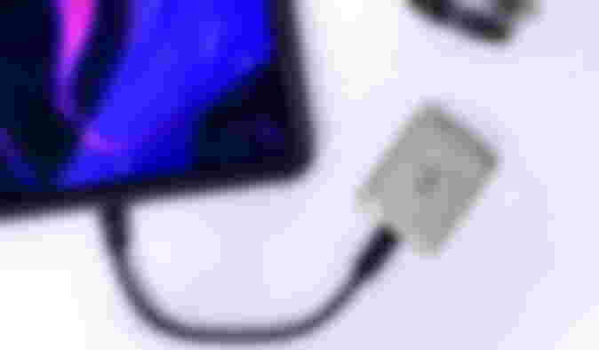 A grey SSD with water spilled on it while attached to an iPad with a black cable.