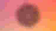 The OpenAI logo in front of a red-orange gradient background