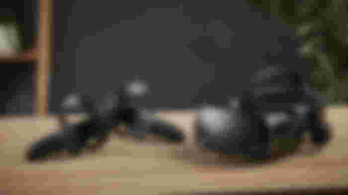 A black VR headset and controllers sat on a light brown wood table.