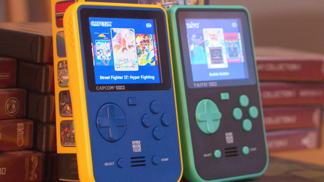 A HyperMegaTech Super Pocket Capcom Edition and Taito Edition against a stack of evercade cases