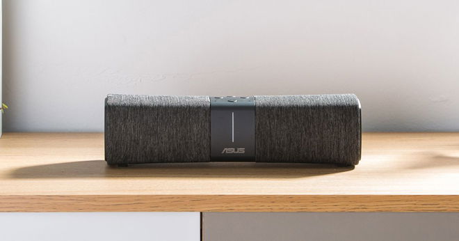 A unique, black, rectangular WiFi router sat on a light brown wooden table.