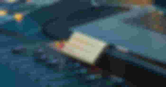 A cream Samsung SSD plugged into and leaning against a laptop.