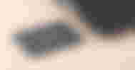 A grey, rectangular SSD with lighter grey branding on top next to a black and grey laptop.