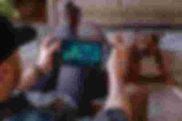 A man with his feet up, playing Steam Deck, while his dog lies on the floor looking at him - Steam Deck emulation