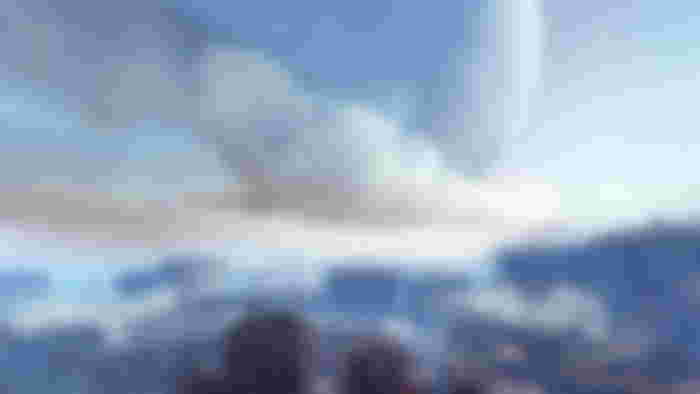 A view over a city, with clouds in-between buildings. In the sky is a huge moon. - Destiny 2 error code Marmot