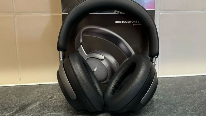 Bose QuietComfort Ultra Headphones in front of the box and a tiled wall