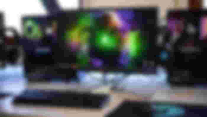 Black flatscreen monitor on a desk with a black keyboard, mouse, mouse mat, and PC.