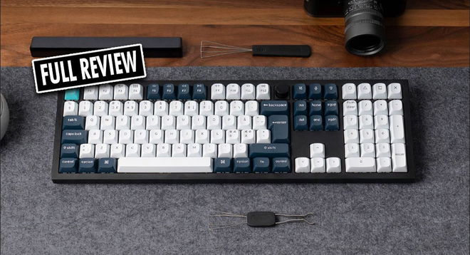 A black keyboard with white, navy, and turquoise keycaps with a black and white "FULL REVIEW" label in the corner