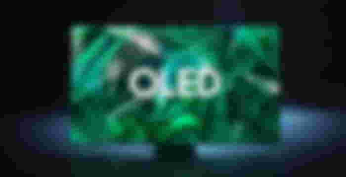 Image of a large flatscreen Samsung TV featuring OLED in white text on the display in front of a green backdrop.