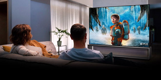 Image of two people sitting on a sofa in front of an LG TV with a Netflix advert on the display featuring a kid in an orange space suit.