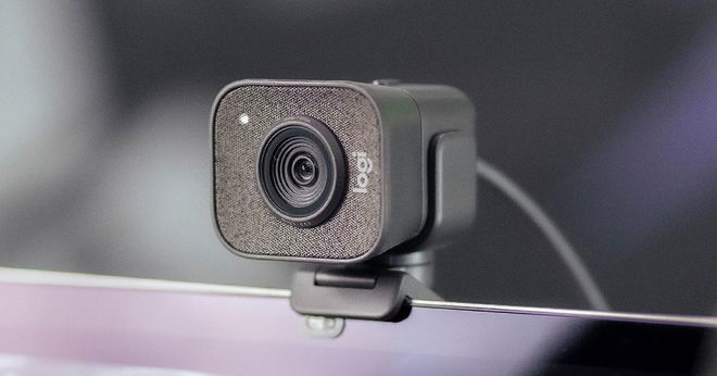 A black square-shaped wired webcam mounted on top of a monitor.
