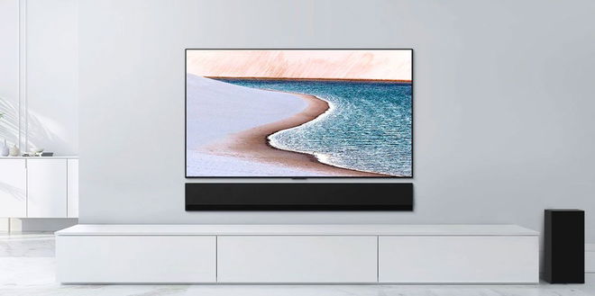 Image of a flatscreen TV featuring a beach on the display on a white shelf with a black soundbar.