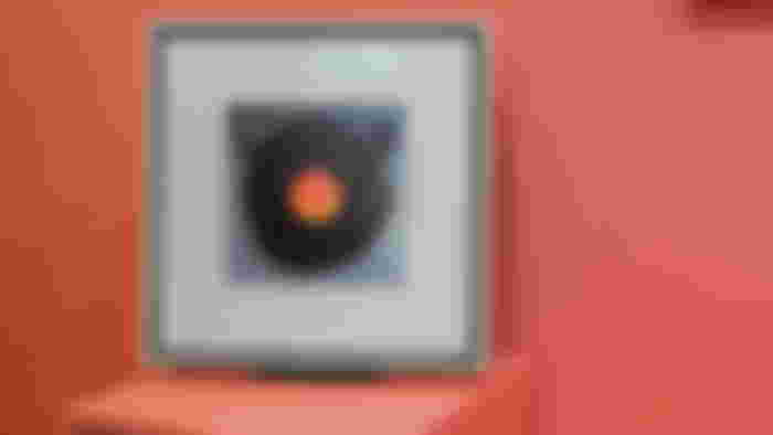 A samsung music frame speaker resting against an orange wall